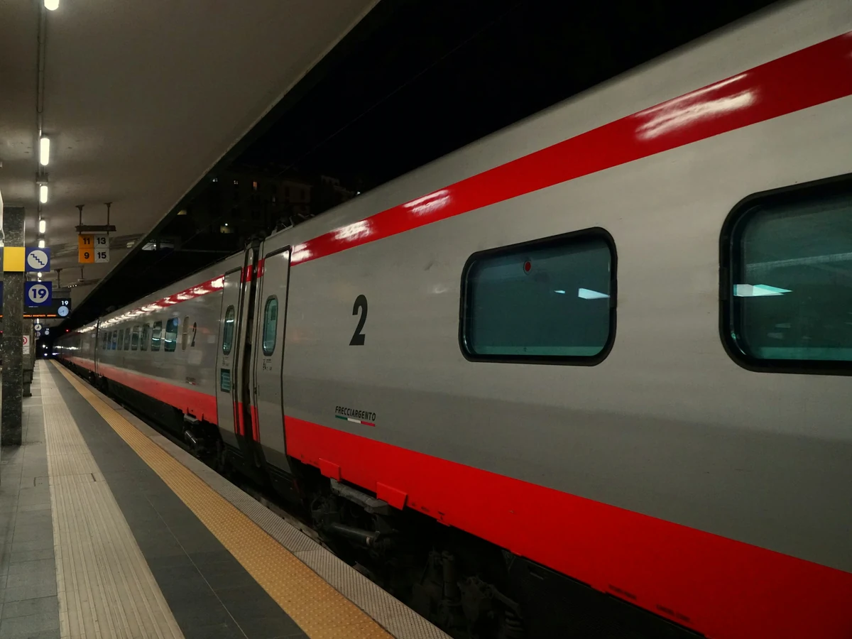 Trenitalia Le Frecce high-speed train waiting at a station platform at night